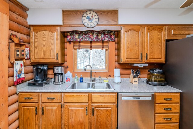 kitchen featuring brown cabinetry, stainless steel appliances, a sink, and light countertops