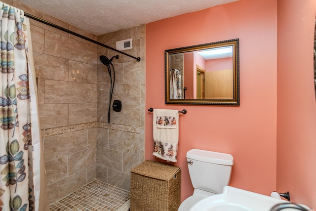 full bath featuring toilet, a shower stall, visible vents, and a textured ceiling