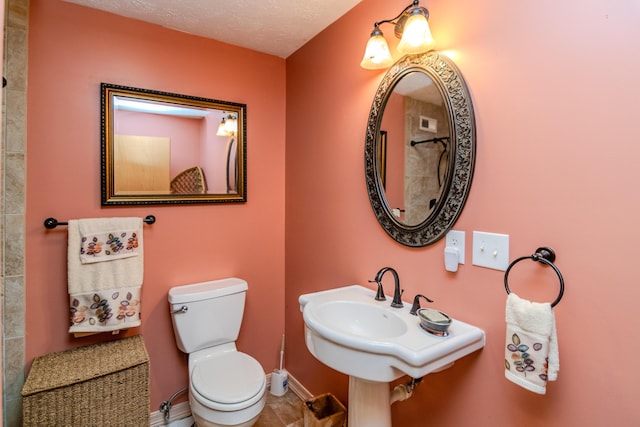 bathroom with toilet, baseboards, and a textured ceiling