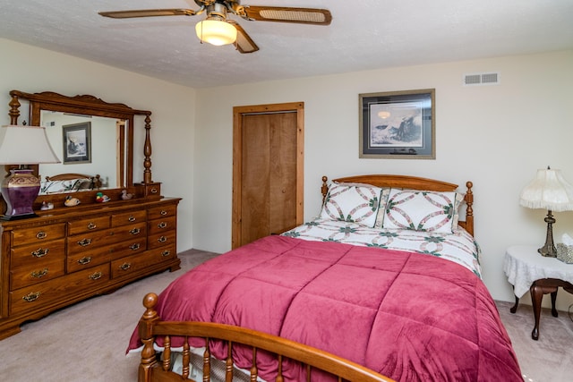 bedroom with a ceiling fan, a closet, visible vents, and light carpet