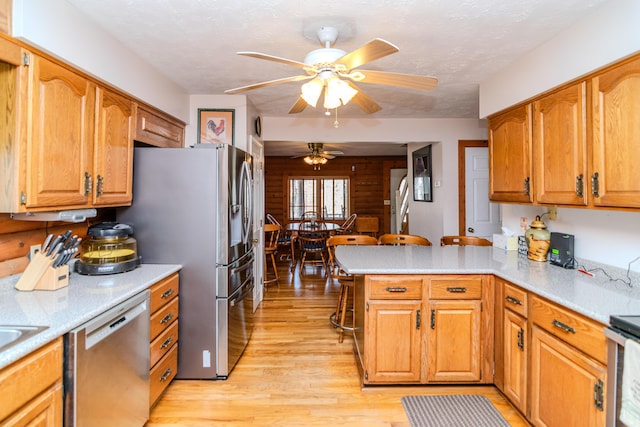 kitchen with a peninsula, light wood-style flooring, stainless steel appliances, and light countertops