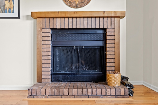 interior details with a brick fireplace, wood finished floors, and baseboards