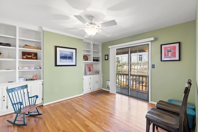 sitting room featuring baseboards, ceiling fan, built in shelves, and light wood-style floors