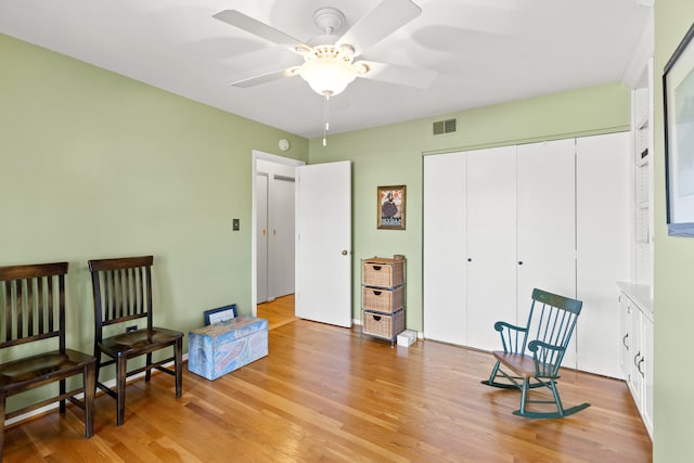 living area featuring a ceiling fan, visible vents, and light wood-style flooring