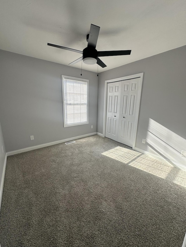 unfurnished bedroom with ceiling fan, visible vents, baseboards, a closet, and carpet