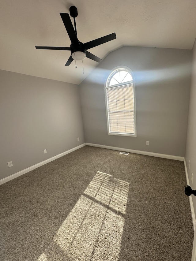 empty room with carpet floors, baseboards, vaulted ceiling, and a ceiling fan