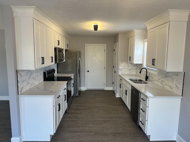 kitchen with white cabinets, appliances with stainless steel finishes, light stone counters, and a sink