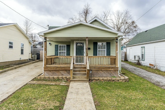 view of front facade with covered porch, driveway, a front yard, and cooling unit