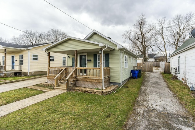 view of front facade with driveway, fence, a porch, and a front yard