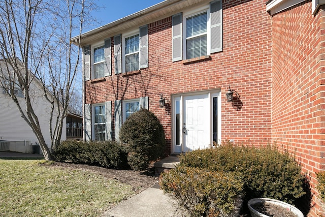 view of front of property with brick siding, a front yard, and central air condition unit