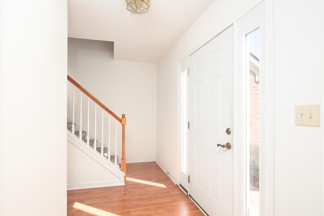 foyer with stairs, wood finished floors, and baseboards