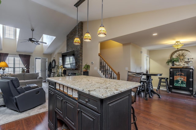 kitchen with a skylight, open floor plan, a center island, dark wood finished floors, and decorative light fixtures