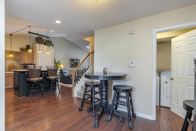 kitchen featuring washer and clothes dryer, a breakfast bar area, brown cabinets, light countertops, and pendant lighting