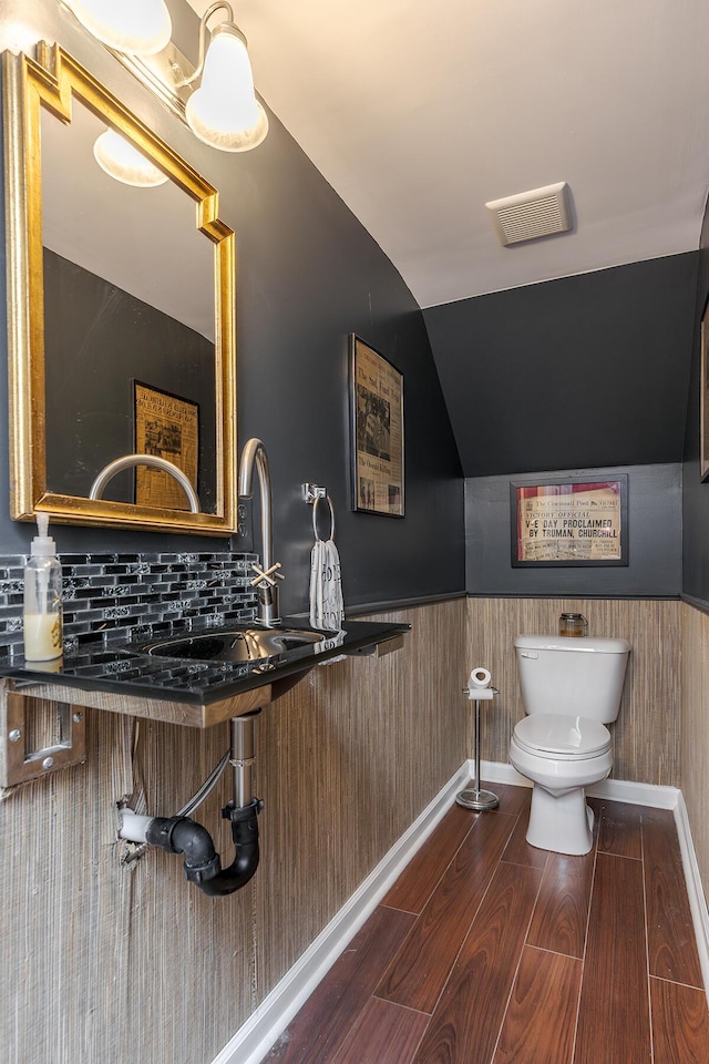 bathroom featuring lofted ceiling, toilet, wood finished floors, visible vents, and wainscoting