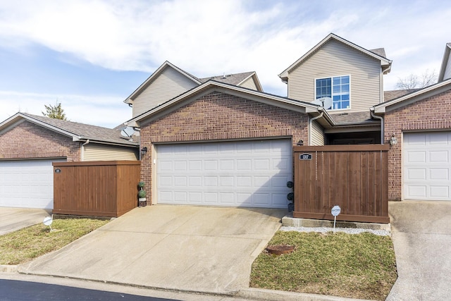 view of front of home with concrete driveway, brick siding, an attached garage, and fence