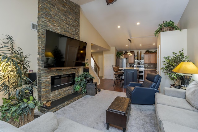 living room featuring high vaulted ceiling, a fireplace, visible vents, stairs, and dark wood finished floors