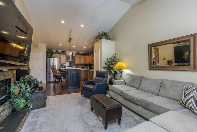 living room with high vaulted ceiling, recessed lighting, a fireplace, and wood finished floors