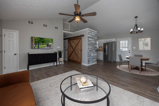 living room with dark wood finished floors, visible vents, and a barn door