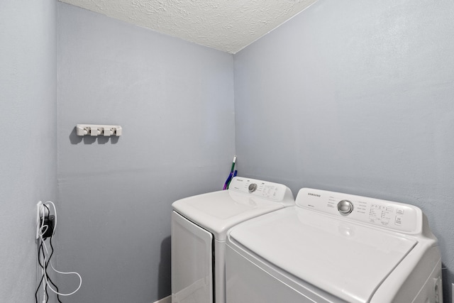 washroom featuring a textured ceiling, laundry area, and washing machine and dryer