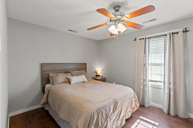 bedroom featuring a textured ceiling, wood finished floors, visible vents, and baseboards