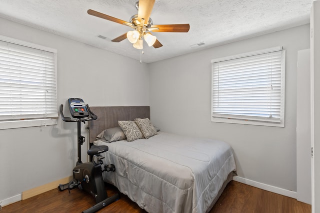 bedroom featuring a textured ceiling, wood finished floors, visible vents, and baseboards