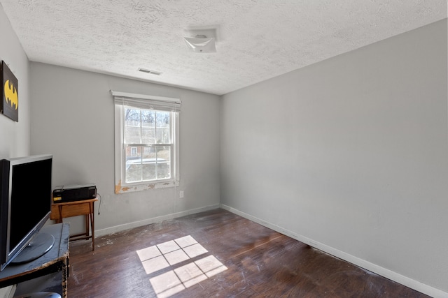 interior space featuring a textured ceiling, wood finished floors, visible vents, and baseboards