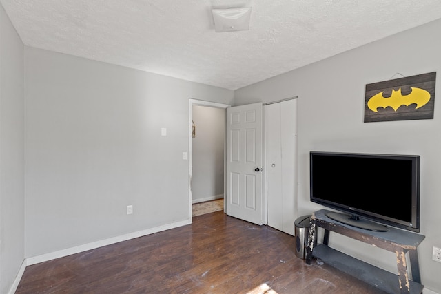 bedroom with dark wood-style floors, a closet, a textured ceiling, and baseboards