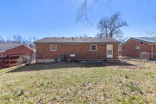 back of house with brick siding, a lawn, fence, and central air condition unit