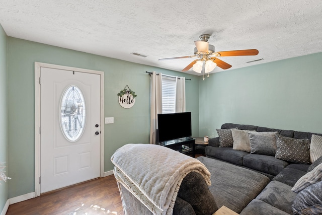 living area with dark wood finished floors, visible vents, and baseboards