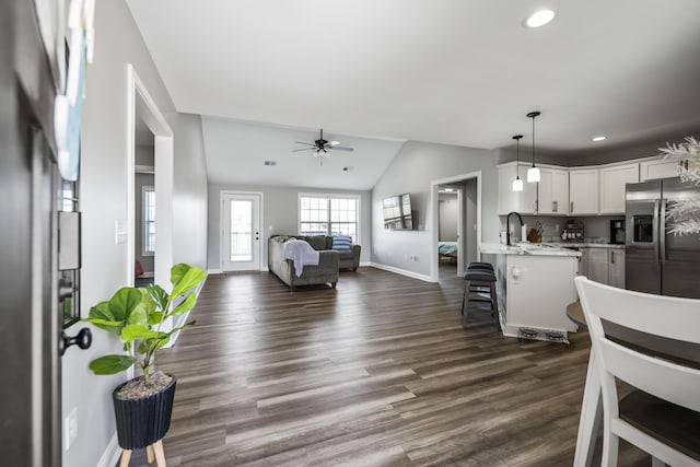 living area featuring baseboards, a ceiling fan, dark wood-type flooring, vaulted ceiling, and recessed lighting