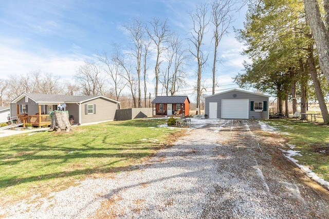 view of front facade with a garage, an outdoor structure, fence, driveway, and a front yard