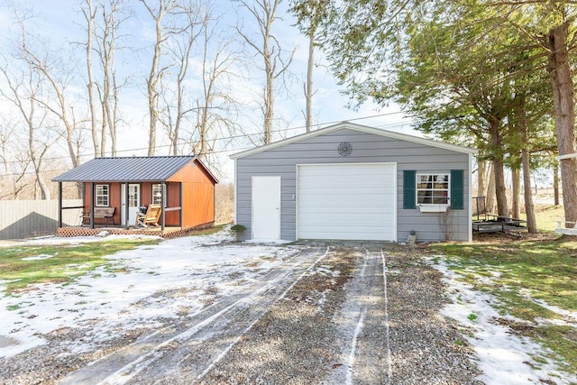 view of front of house featuring concrete driveway, an outdoor structure, a detached garage, and fence