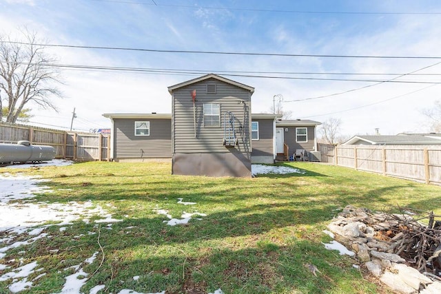 rear view of property with a fenced backyard and a yard