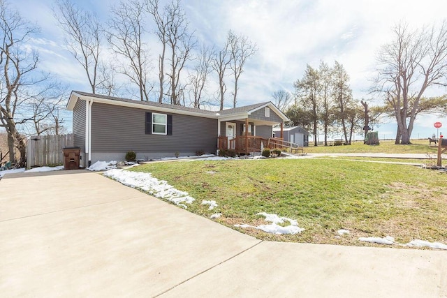 view of front of property with covered porch, fence, and a front lawn