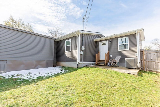 rear view of house featuring a yard, entry steps, central AC, and fence