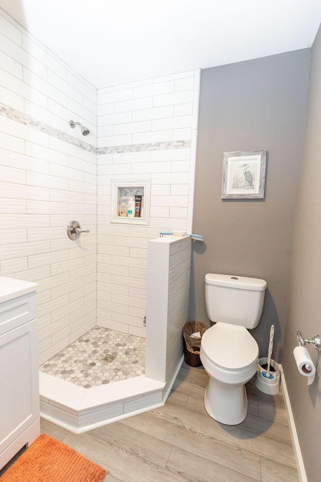 full bath with a stall shower, baseboards, toilet, wood finished floors, and vanity