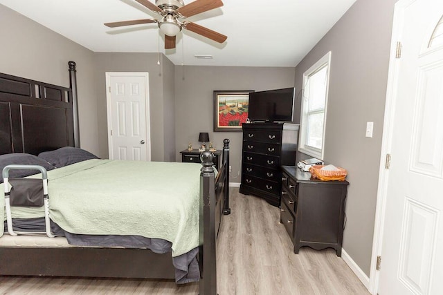 bedroom featuring light wood finished floors, a ceiling fan, visible vents, and baseboards