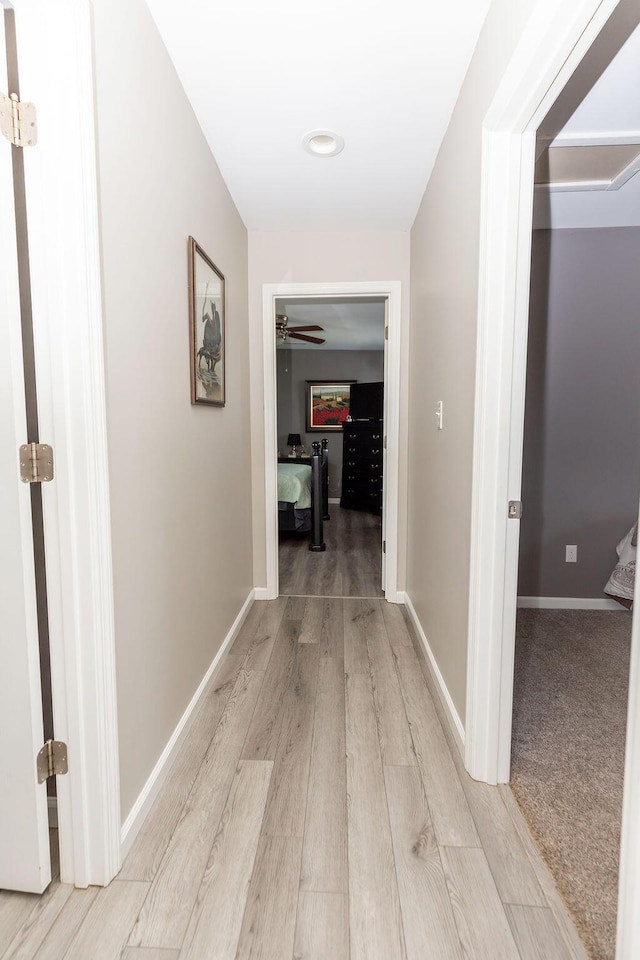 corridor featuring light wood-type flooring and baseboards