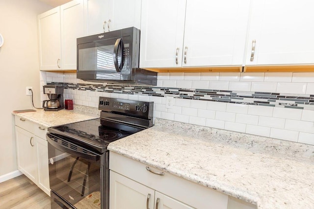 kitchen with light stone counters, white cabinetry, light wood-style floors, decorative backsplash, and black appliances