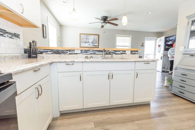 kitchen featuring light stone counters, white cabinets, decorative backsplash, and decorative light fixtures