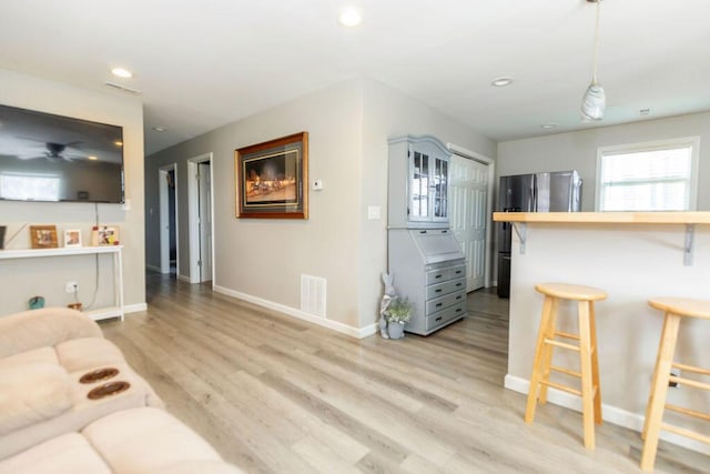 living room with light wood-type flooring, baseboards, visible vents, and recessed lighting