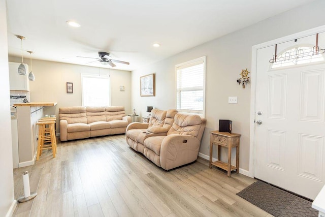 living room with baseboards, recessed lighting, a ceiling fan, and light wood-style floors