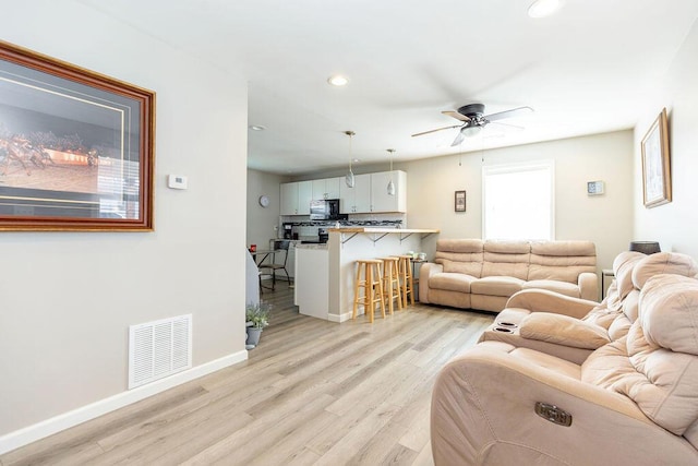 living area featuring visible vents, baseboards, light wood-style flooring, ceiling fan, and recessed lighting