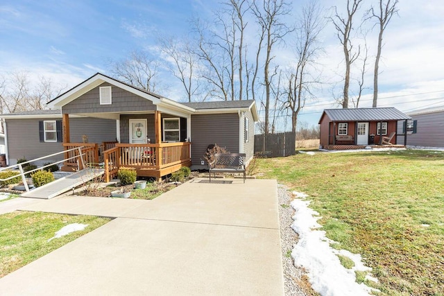 view of front of property featuring fence, a front lawn, concrete driveway, and an outbuilding