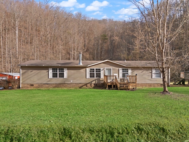 back of house with crawl space, a forest view, a deck, and a yard