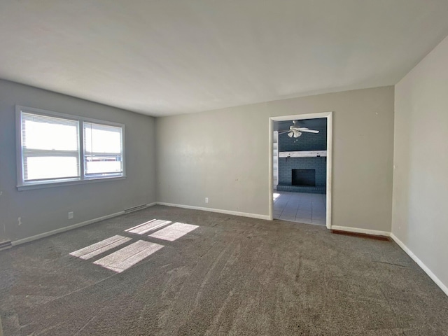 carpeted spare room with a brick fireplace and baseboards