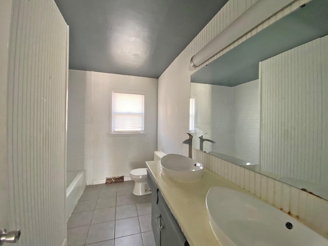 full bath featuring toilet, double vanity, a sink, and tile patterned floors