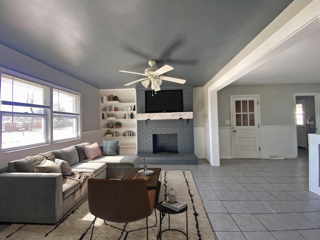 living room featuring a brick fireplace, ceiling fan, visible vents, and light tile patterned flooring