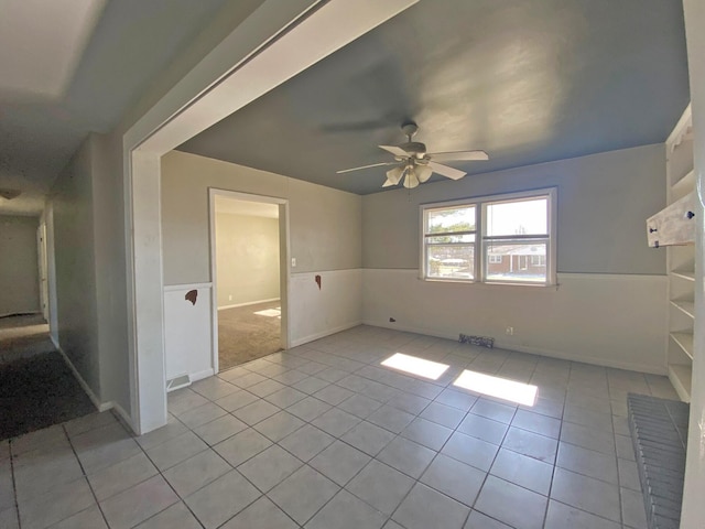 tiled empty room featuring a ceiling fan