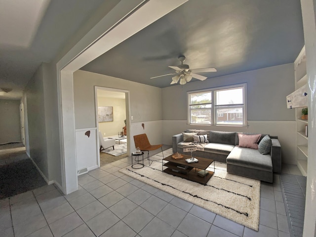 living area featuring a wainscoted wall, a ceiling fan, and tile patterned floors